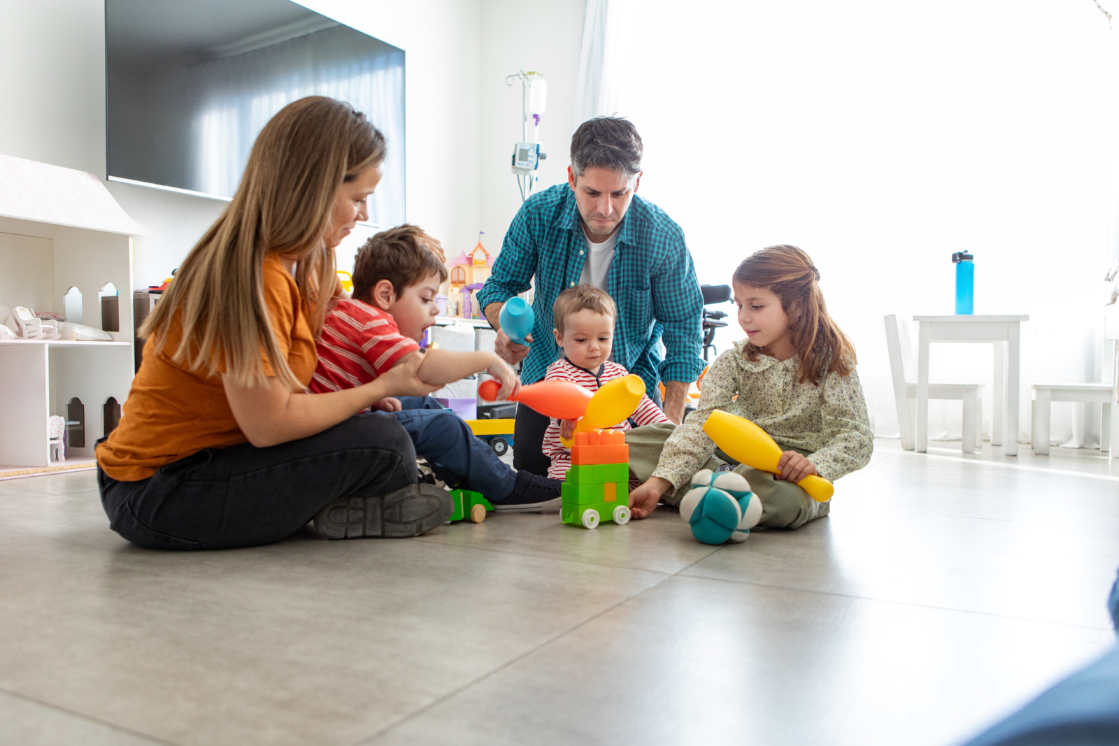 A husband and wife play with toys their three young children