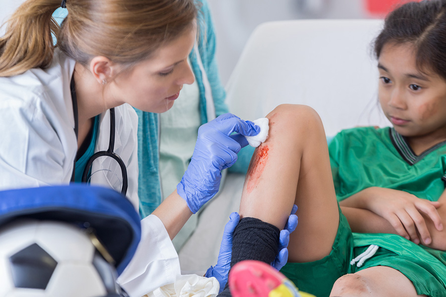A doctor cleans a red, swollen skin area on a child's leg, illustrating symptoms of a skin infection