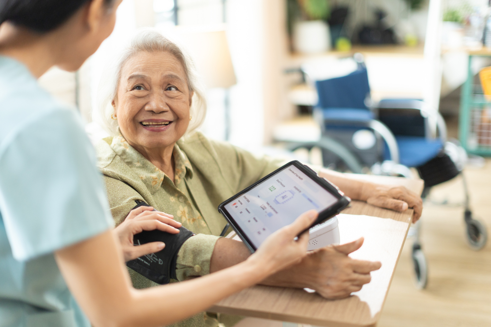 Female nurse holds an iPad while conversing with a patient, capturing the conversation through AI